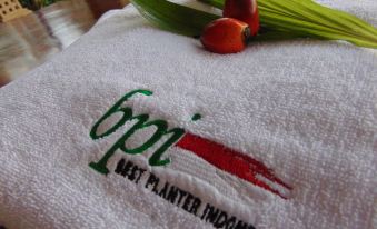a white towel with a green logo and red accents , along with two bananas at Wisma BPI