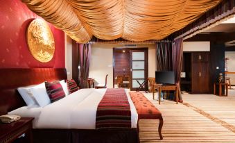 a luxurious hotel room with a large bed , wooden furniture , and a unique ceiling design at Paradise Hotel