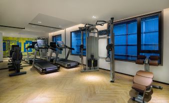 There is a gym adjacent to another room, featuring large windows and exercise equipment at Kasion Pugis Hotel (Yiwu International Trade City)