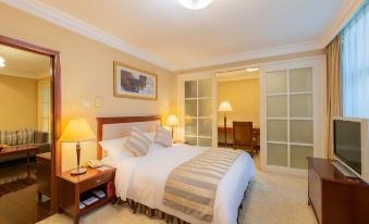 In the middle room, there is a large bed with lamps on both sides and sliding glass doors at Metropark Hotel Shenzhen