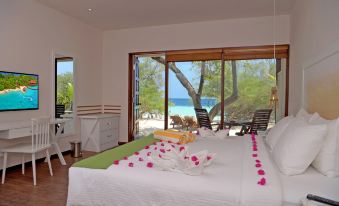 a bedroom with a bed , flowers on the bed , and a view of the ocean through large windows at Eriyadu Island Resort