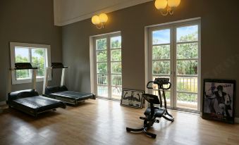 A home gym with large windows and hardwood floors is located in the middle, alongside an empty space at Regency Art Hotel