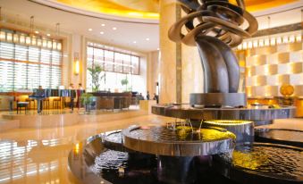 The lobby features a spacious room with tables and chairs, accompanied by an ornate fountain at New Joyful Hotel
