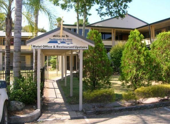 "a house with a sign that says "" motel office & restaurant upstairs "" in front of it" at Bucketts Way Motel