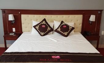 "a bed with a white comforter and two brown pillows with floral designs , featuring the words "" paradise hotel "" written on the bed" at Paradise Hotel Bac Kan