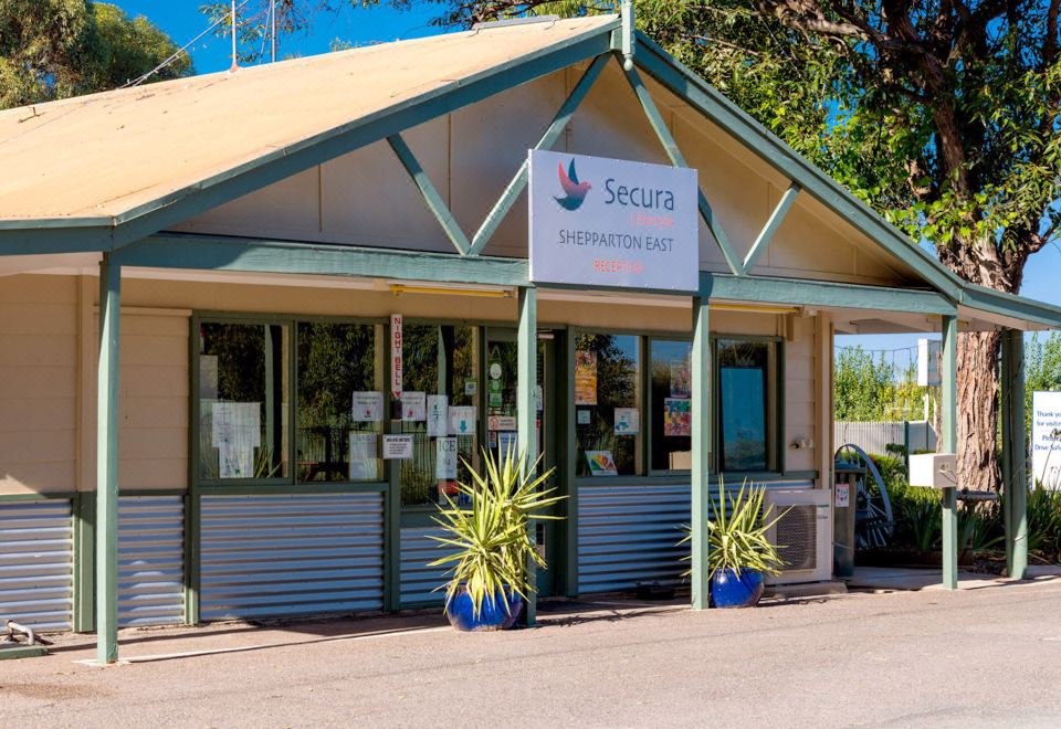 "a small building with a sign that reads "" secura of the west "" is surrounded by potted plants" at Shepparton Holiday Park and Village