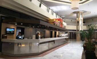 a large hotel lobby with a marble floor , a reception desk , and several chairs arranged around it at Impiana Hotel Ipoh