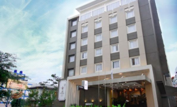 a modern , white - colored building with multiple floors and balconies , surrounded by lush greenery and a blue sky at Pranaya Boutique Hotel