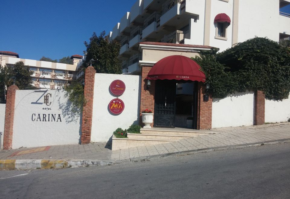 a brick building with a red awning , located on the side of a street near a body of water at Hotel Carina