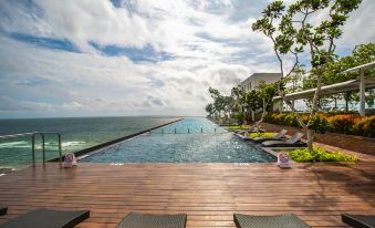 a large swimming pool surrounded by lounge chairs and umbrellas , with the ocean visible in the background at Marino Beach Colombo