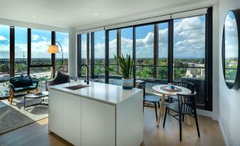 a modern kitchen with white cabinets and a dining area featuring a table and chairs at Punthill Ivanhoe