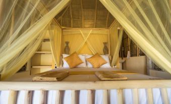a bed with a canopy and yellow mosquito netting is shown in a room with white walls at Royal Beach