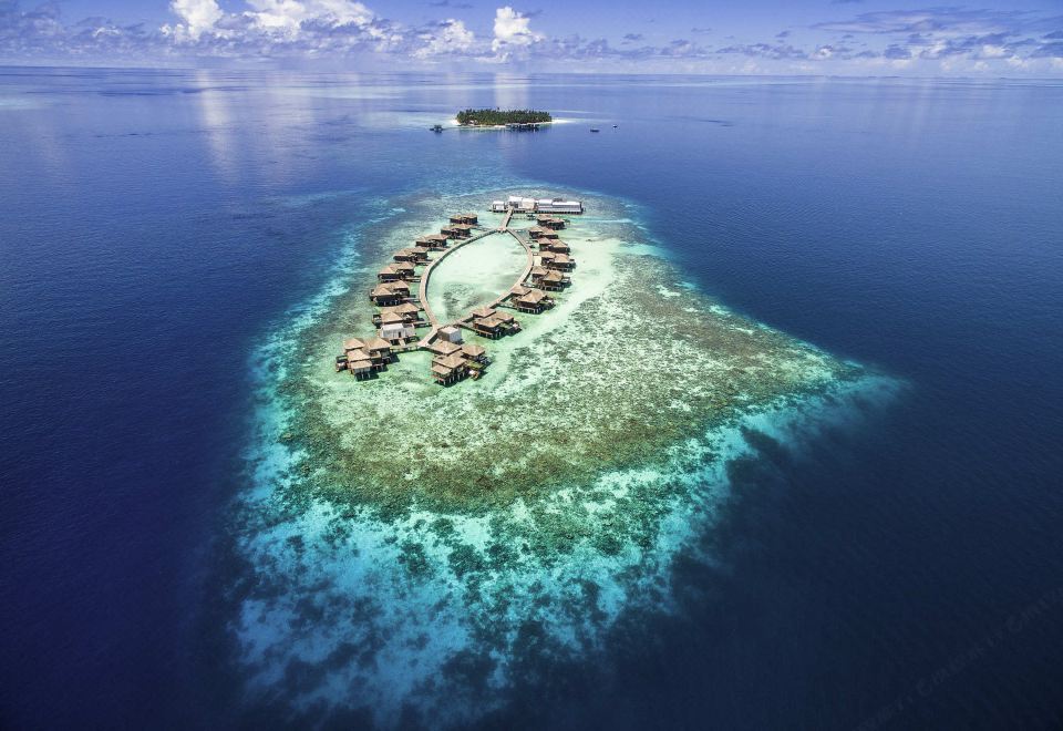aerial view of a small island surrounded by clear blue water , with several buildings on it at Raffles Maldives Meradhoo Resort