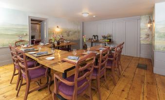 a dining room with a wooden dining table surrounded by chairs , and a stove in the background at Colby Hill Inn