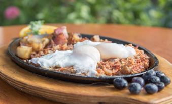 a cast iron skillet filled with breakfast food , including eggs , potatoes , and sausage , placed on a dining table at Woodstock Inn, Station and Brewery