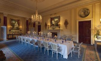 a long dining table set for a formal dinner , with multiple chairs arranged around it at Ballyfin Demesne