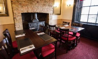 a dining room with a table set for dinner , surrounded by chairs and a fireplace at The Oddfellows Arms
