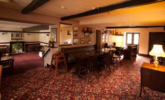 a dimly lit room with a bar and several chairs , creating a cozy atmosphere for patrons at The Punchbowl Inn