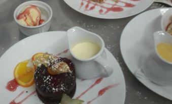 a dining table with three plates of food , each containing a different dessert and a cup of coffee at Rose & Crown