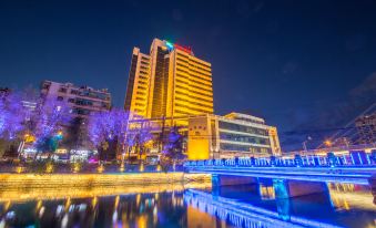 At night, a city is illuminated by blue and white lights on top of its buildings at UChoice Hotel