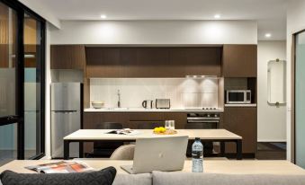 a modern kitchen with a dining table , couch , and living area in the background at Quest Williamstown North