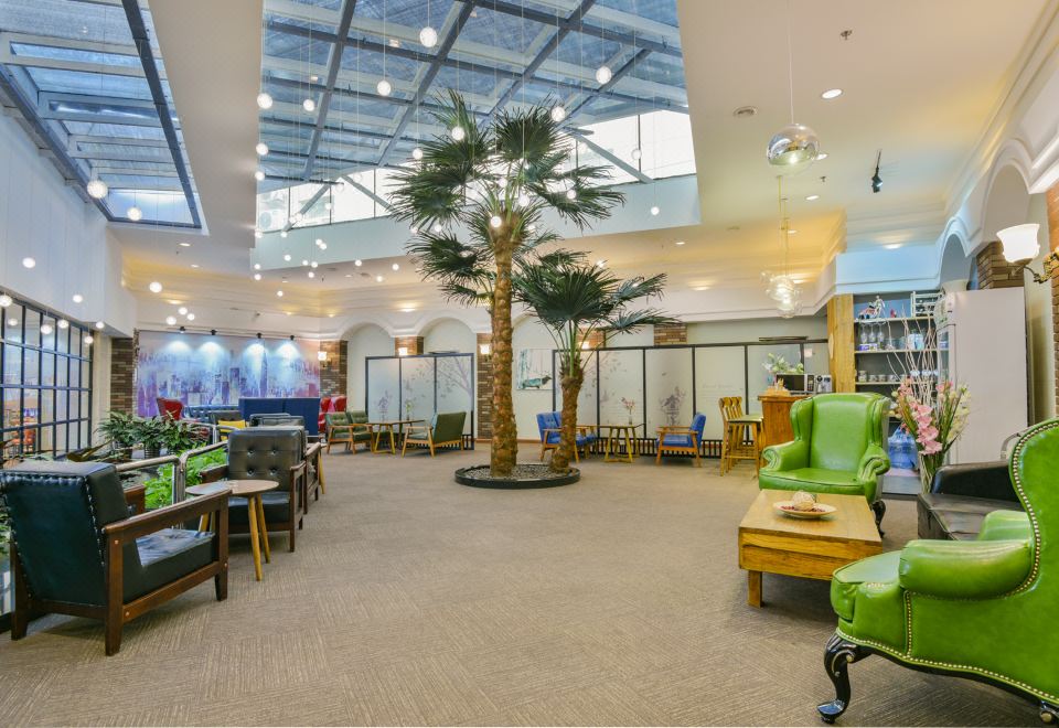 A room with chairs and tables in the middle, adjacent to a seating area at Jingcheng Business Hotel (Beijing Shilihe Metro Station)