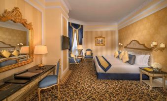 a luxurious hotel room with a large bed , two chairs , and a desk , all decorated in gold and blue at Royal Rose Abu Dhabi