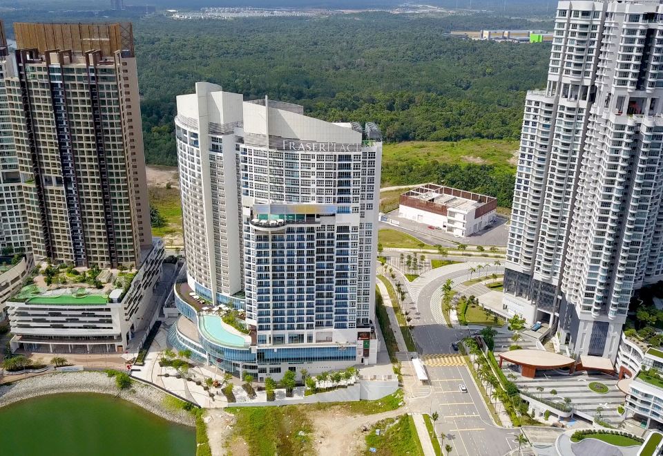 aerial view of a modern building surrounded by trees and water , with a pool in the foreground at Fraser Place Puteri Harbour, Johor