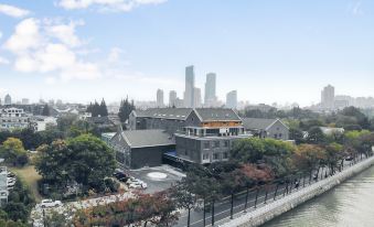 a city skyline with a large building in the foreground and a river in the background at Ji Hotel