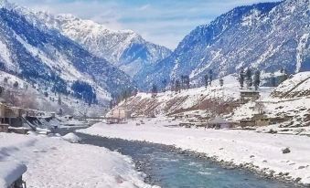 a snow - covered mountain range with a river flowing through it , creating a picturesque winter landscape at Pearl Continental Hotel Malam Jabba