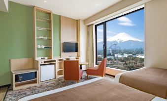 a hotel room with two beds , a desk , and a large window overlooking a mountain at HOTEL MYSTAYS Fuji Onsen Resort