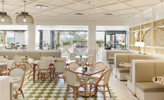 a restaurant with white tables and chairs , green and white checkered floor , and large windows at The Ville Resort - Casino