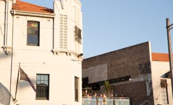 a white building with a red roof and a balcony overlooking the street below , accompanied by people walking around at The Urban Newtown