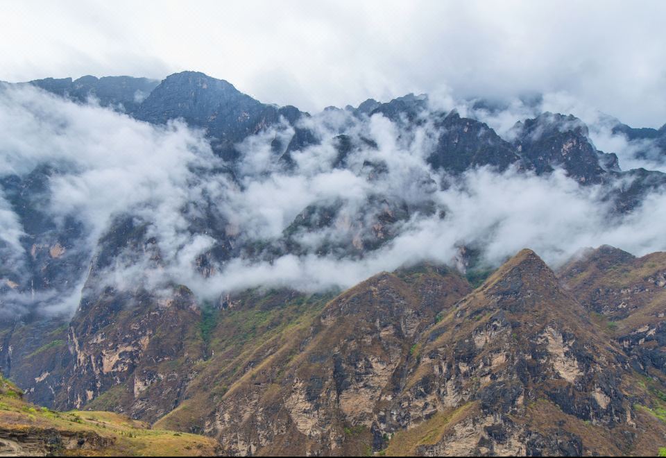 A panoramic view from a high vantage point, overlooking mountains, valleys, and clouds at Tina's Youth Hostel