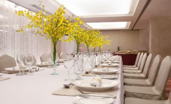 A long table is set for an event with white and yellow place settings on each side at Park Hotel Hong Kong