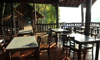 an outdoor dining area at a restaurant , with wooden tables and chairs arranged for guests to enjoy their meal at Borneo Natural Sukau Bilit Resort