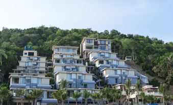 a large beach house is perched on a hill overlooking the ocean , with palm trees in the background at Bandara Villas, Phuket