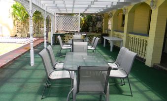 a large patio with a table and chairs , surrounded by a white railing and greenery at Tropic Coast Motel