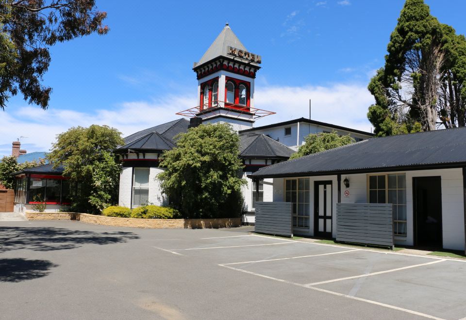 a tall building with a clock tower on top , surrounded by trees and a parking lot at Hobart Tower Motel