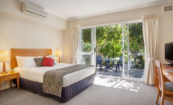 a bedroom with a bed and a sliding glass door leading to a patio area at C Mandurah Apartment Resort