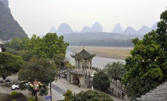 a scenic view of a park with a gazebo and people walking around , surrounded by mountains and a river at Riverview Hotel