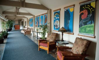 a room with two wooden chairs and a couch , along with paintings on the wall at St. Eugene Golf Resort & Casino