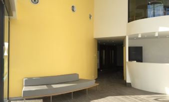 a modern office building with a yellow wall , a gray bench , and a white desk at ValueSuites Green Square