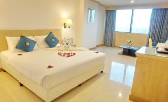 a large bed with a white comforter and blue pillows is in a hotel room at Bay Hotel Srinakarin