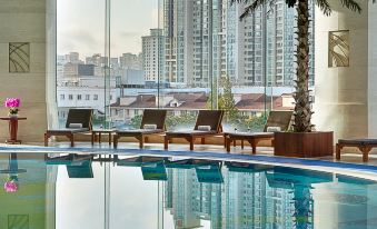 The modern bedroom features a swimming pool with large windows that offer views of the city and surrounding buildings at Pullman Shanghai Skyway Hotel