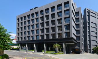 a modern , gray building with multiple floors and balconies , situated on a street with cars parked on the side at Platinum Hotel