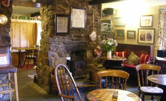 a cozy stone fireplace with a fire inside , surrounded by wooden furniture and framed pictures on the wall at The Lamb Inn