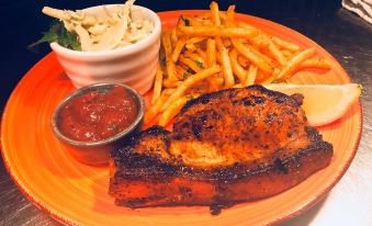 a plate of food with meat , fries , and a side dish is presented on an orange plate at The Black Horse Inn