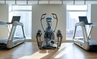a spacious gym with large windows and a centrally located exercise machine at base SUHE Serviced Apartment