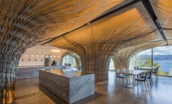 a modern restaurant with a bar and dining area under a tree - like structure , where people are sitting and enjoying their meals at WE Hotel Toya